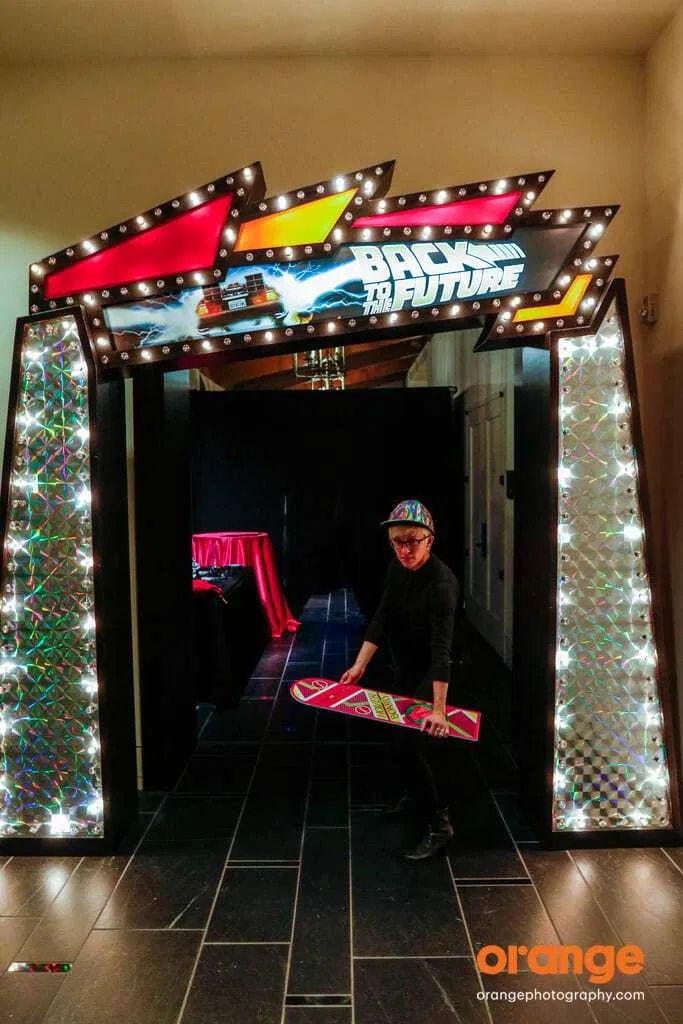 a man holding a skateboard in front of a lit up entrance