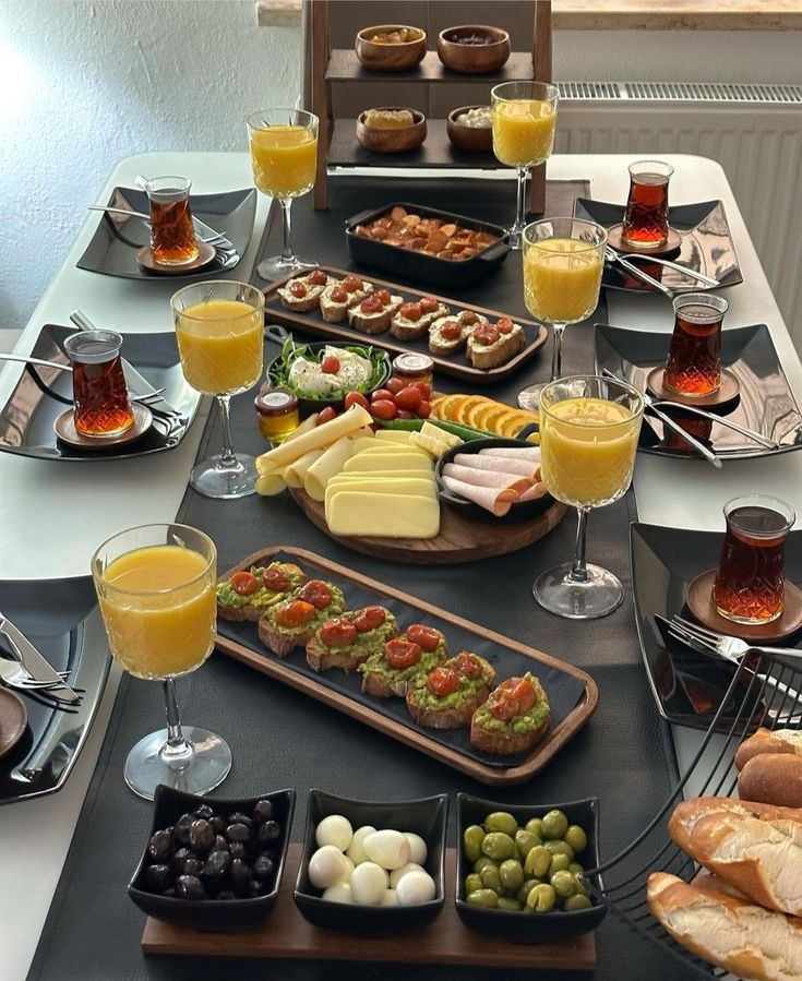 a table filled with different types of food and glasses of orange juice on top of it