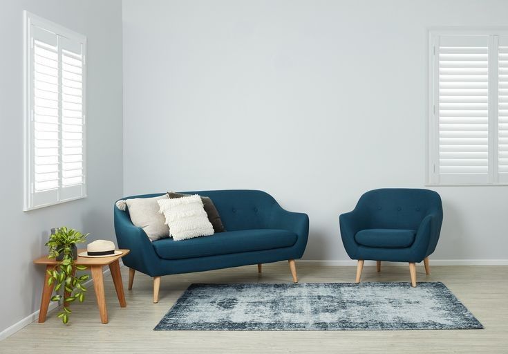 two blue chairs sitting next to each other on top of a rug in a living room