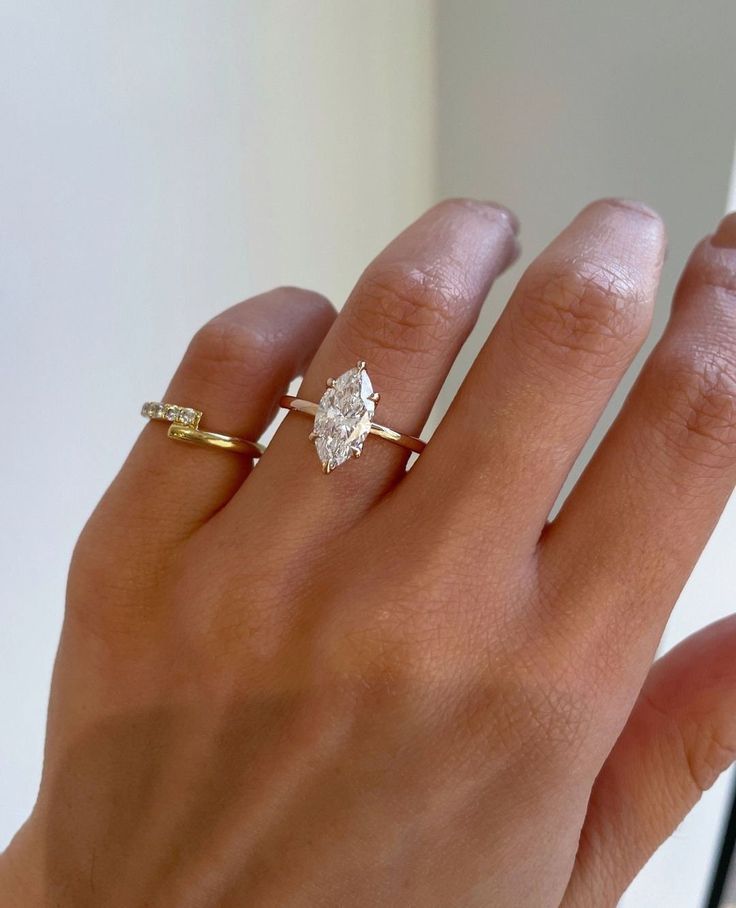 a woman's hand with two different rings on her left and the middle finger