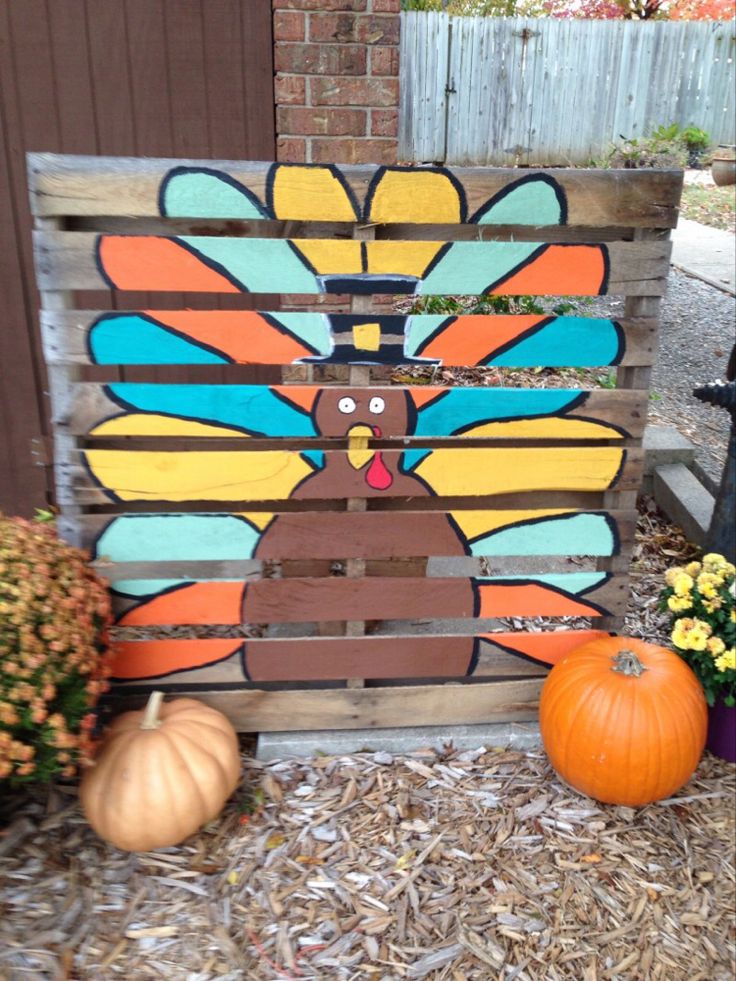 a wooden pallet with a turkey painted on it next to pumpkins and flowers