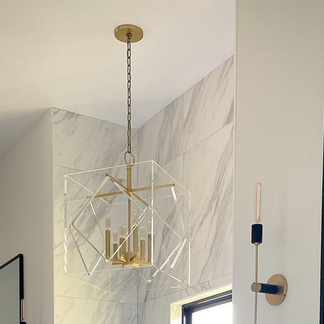 a chandelier hanging from the ceiling in a bathroom with marble walls and floors