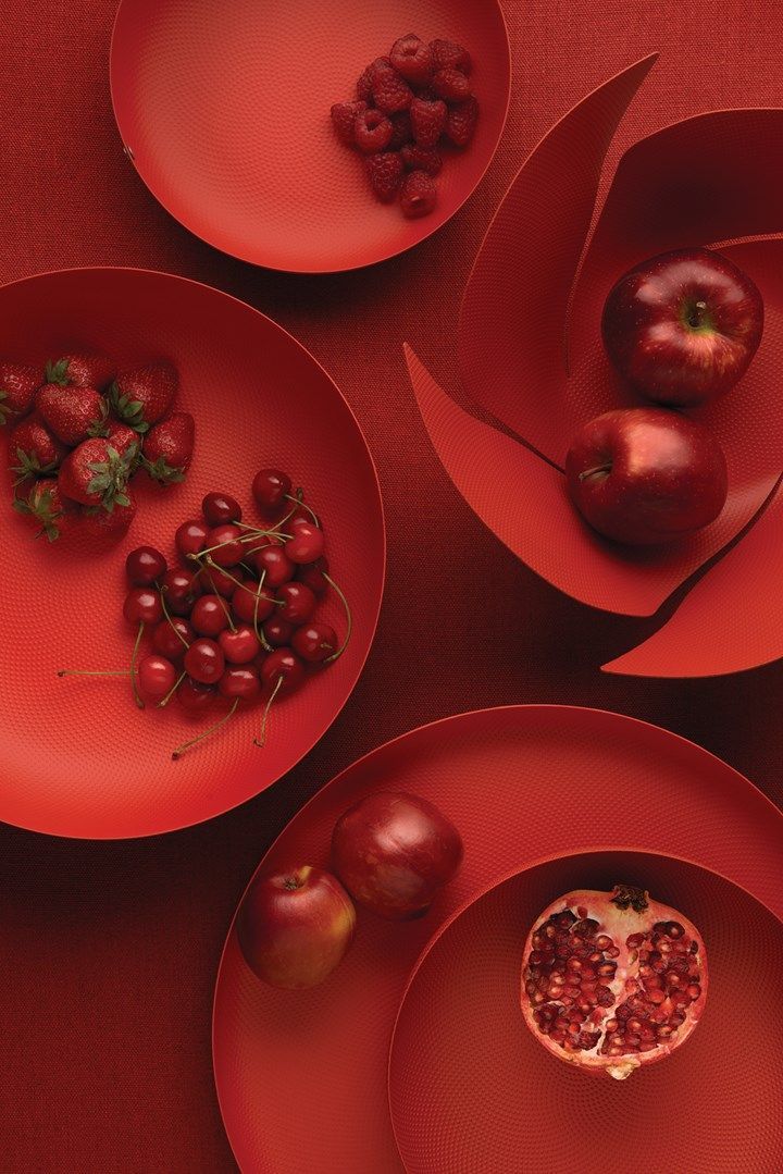 three red plates with fruit on them and one has a pomegranate in the middle