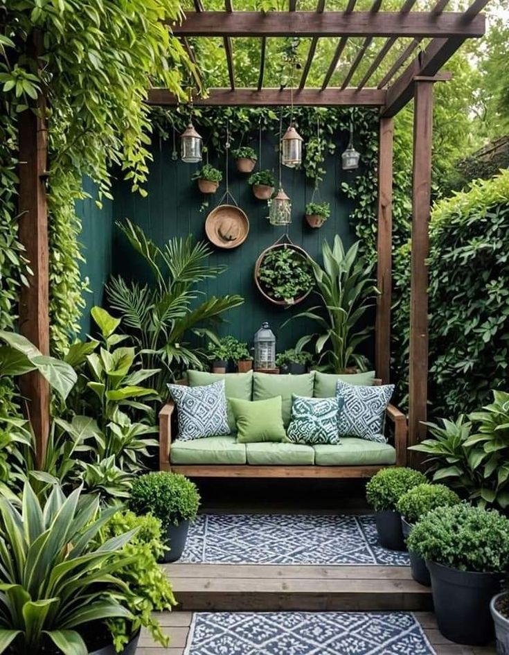 an outdoor seating area with plants and potted plants on the wall, surrounded by greenery