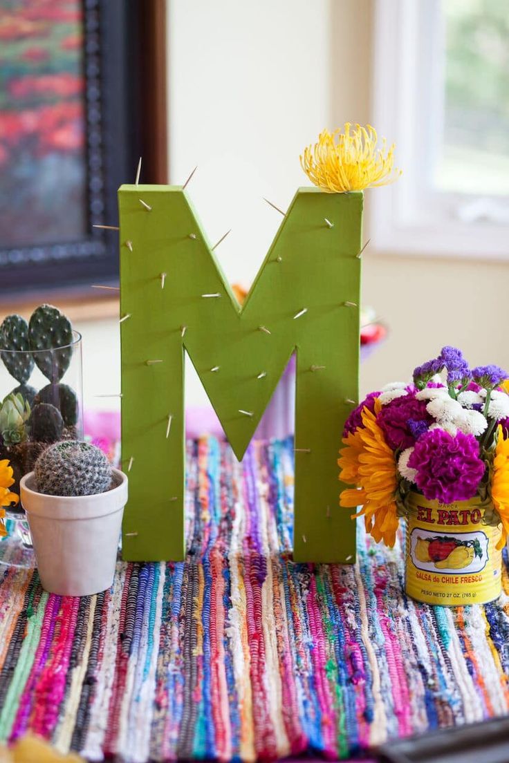 the letter m is made out of green paper and sits on a colorful tablecloth