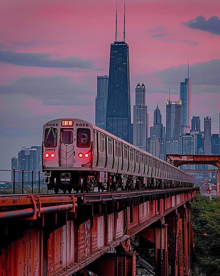 a train traveling over a bridge with the city skyline in the background