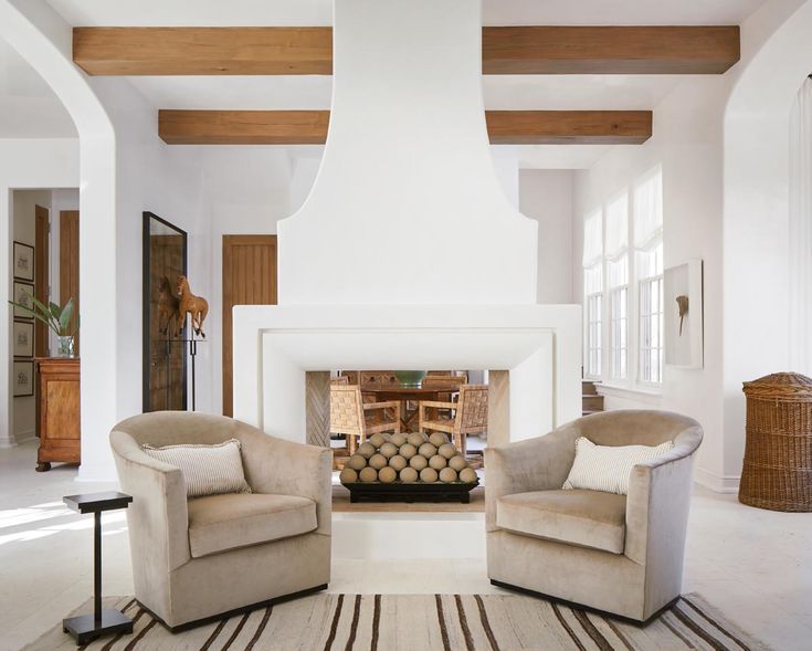 a living room with two chairs and a fire place in the middle of the room