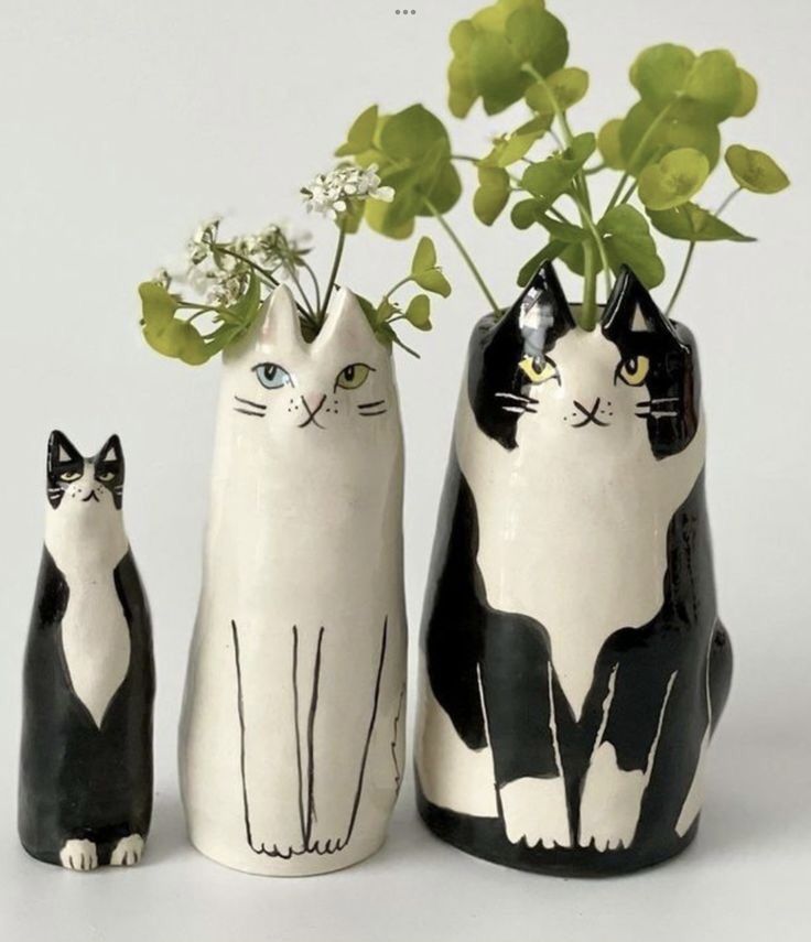 three black and white ceramic cats with flowers in their heads, sitting next to each other