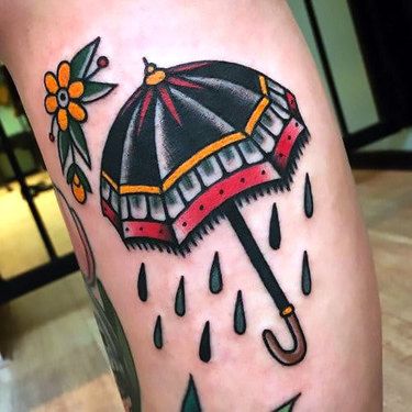 a tattoo with an umbrella and flowers on the leg that is covered in raindrops