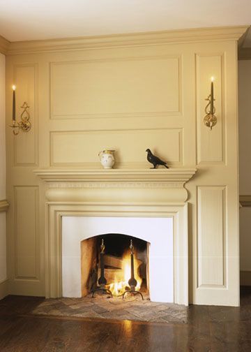 a fire place in the middle of a room with wood flooring and white walls