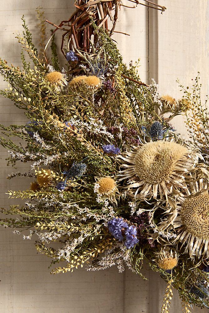 an arrangement of dried flowers hanging from a door