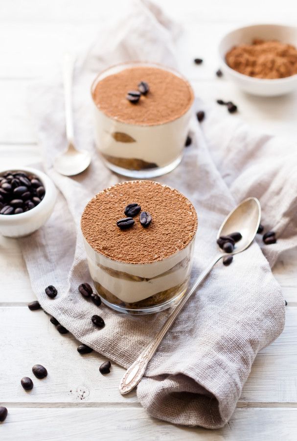 two desserts with coffee beans on the side and spoons next to one another