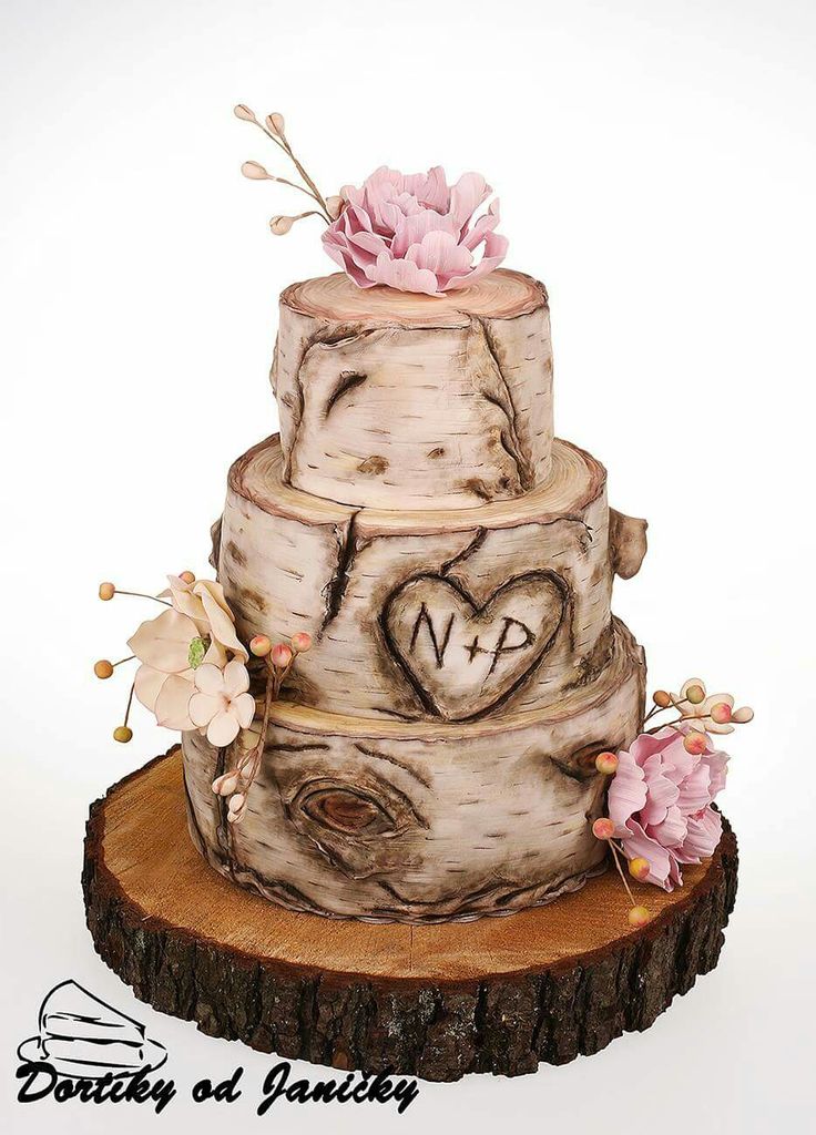 a three tiered wedding cake decorated with flowers and initials on a tree stump slice