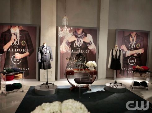 an assortment of women's clothing displayed on display in a store window with chandeliers