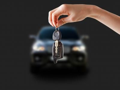 a hand holding a car key in front of a black background