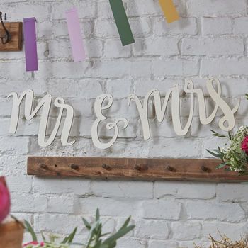 a sign that says mr and mrs hanging on a brick wall next to potted plants