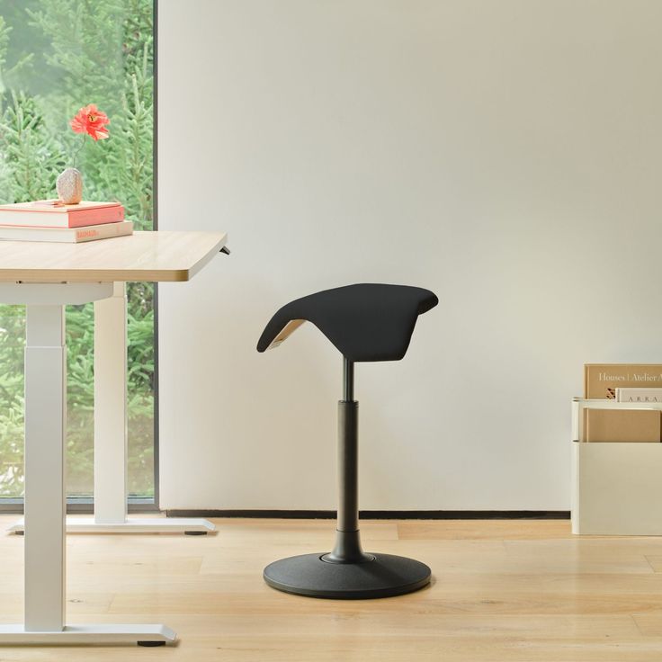 a black chair sitting on top of a hard wood floor next to a white table