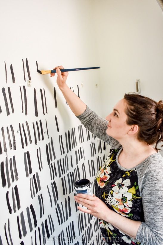 a woman painting a wall with black and white paint