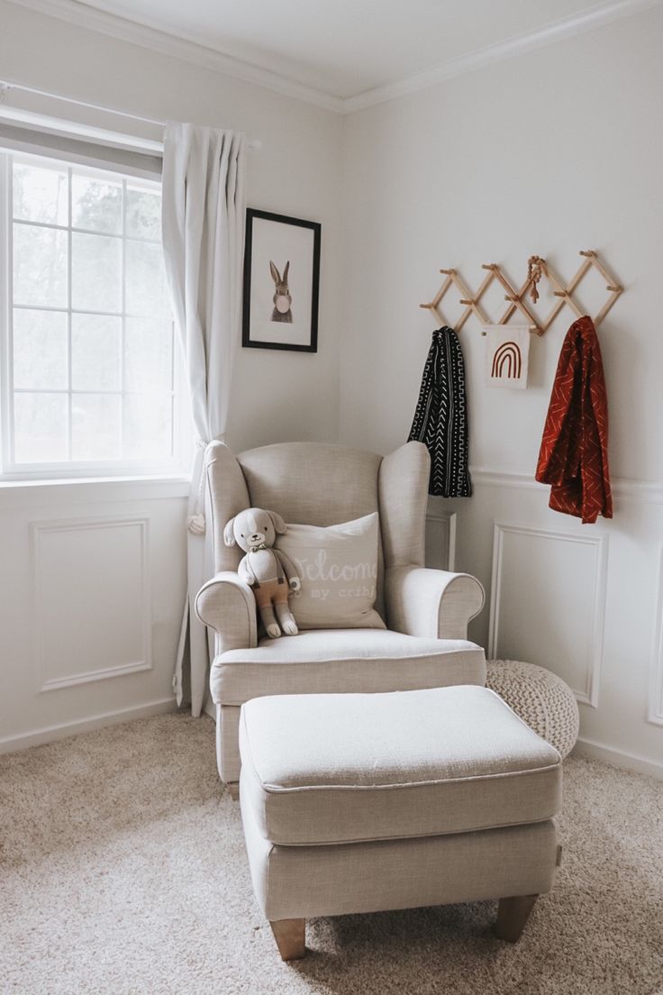 a baby's room with a chair, teddy bear and coat rack