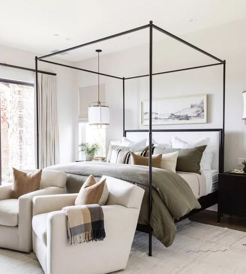 a bedroom with four poster bed, chair and ottoman in front of sliding glass doors