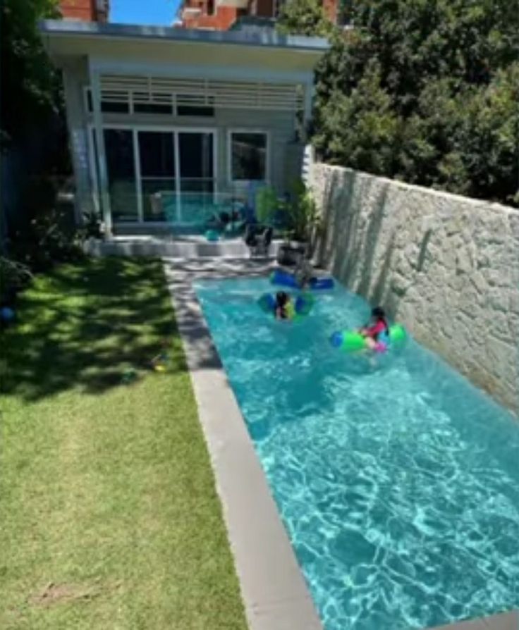 two people are playing in the pool with their boogie boards and water toys while another person watches