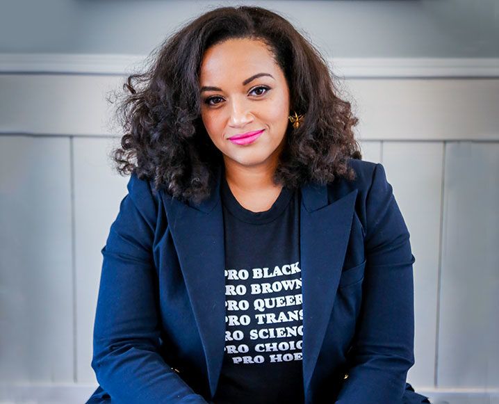 a woman sitting on a bench wearing a black shirt and blue blazer with words printed on it