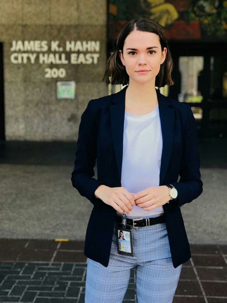 a woman standing in front of a building with her hands on her hips and looking at the camera