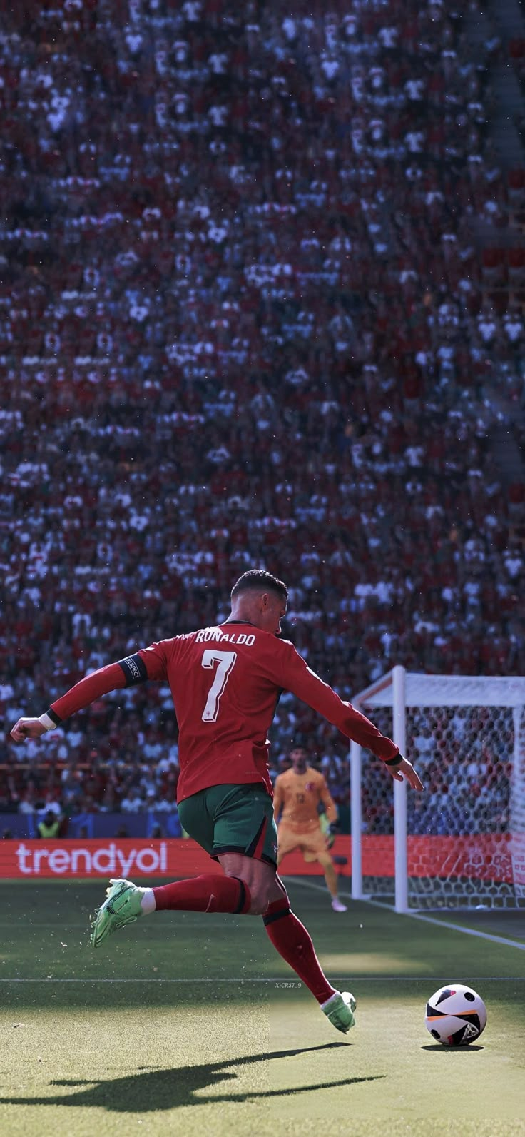 a man kicking a soccer ball on top of a field