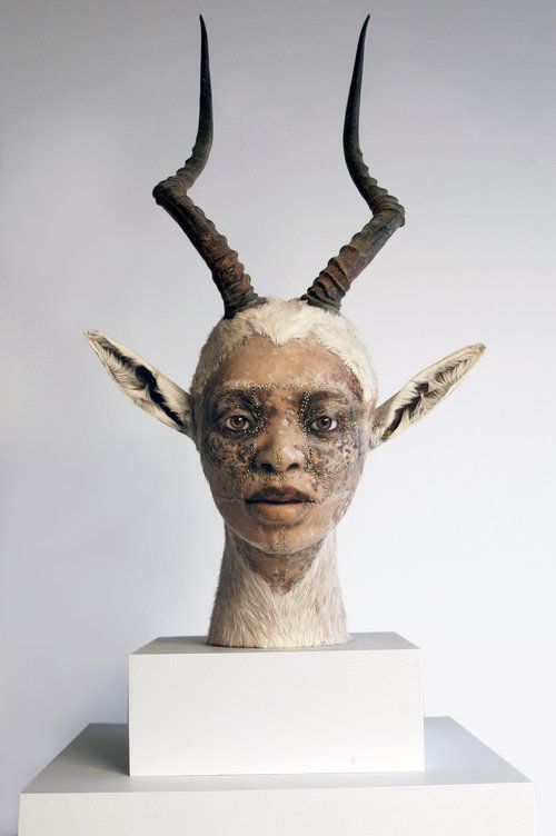 a sculpture of a woman's head with horns on top of a white pedestal