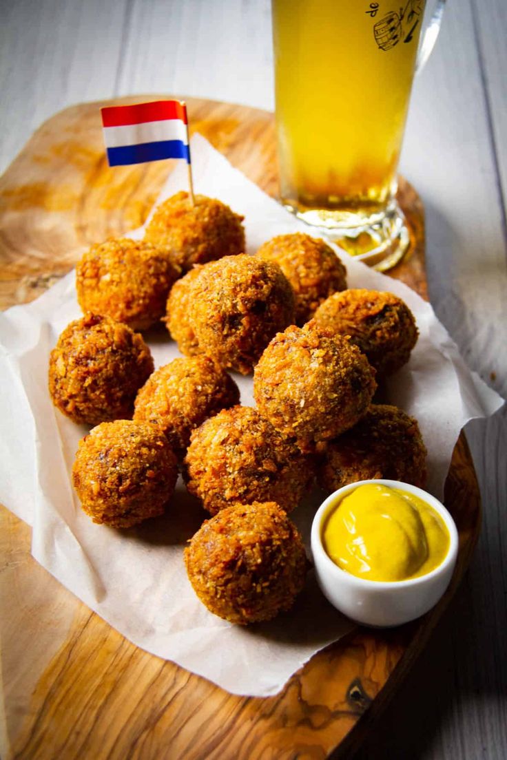 some food is on a wooden tray next to a glass of beer and a flag