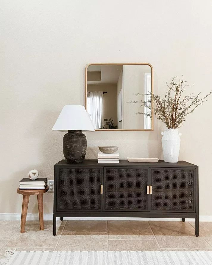 a living room with a large mirror on the wall next to a table and lamp