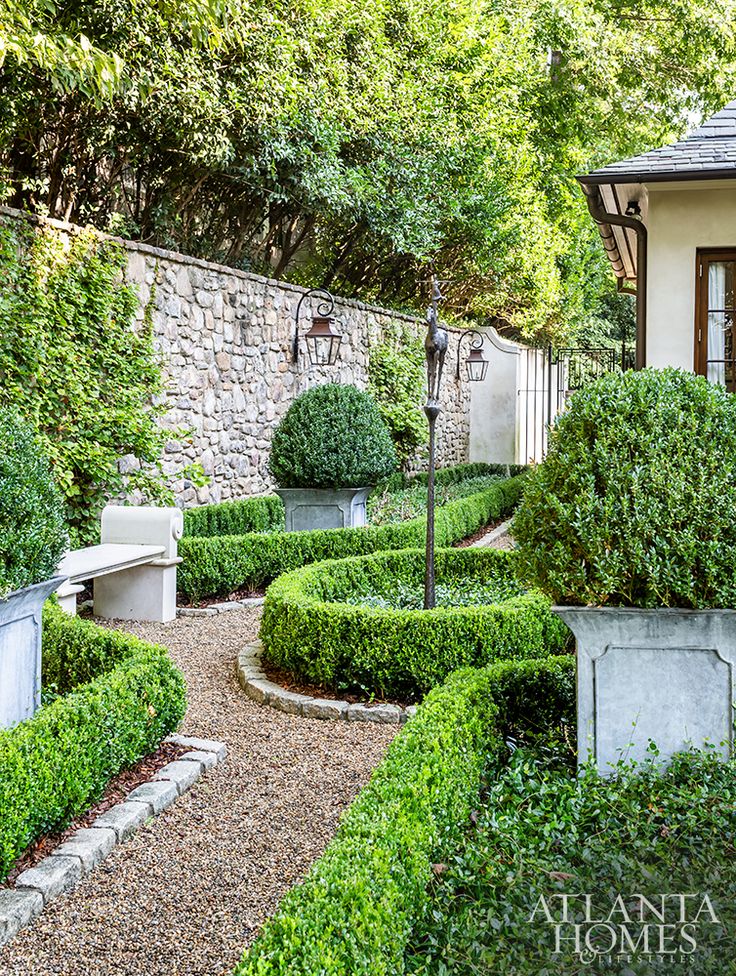 an outdoor garden with hedges and stone walls