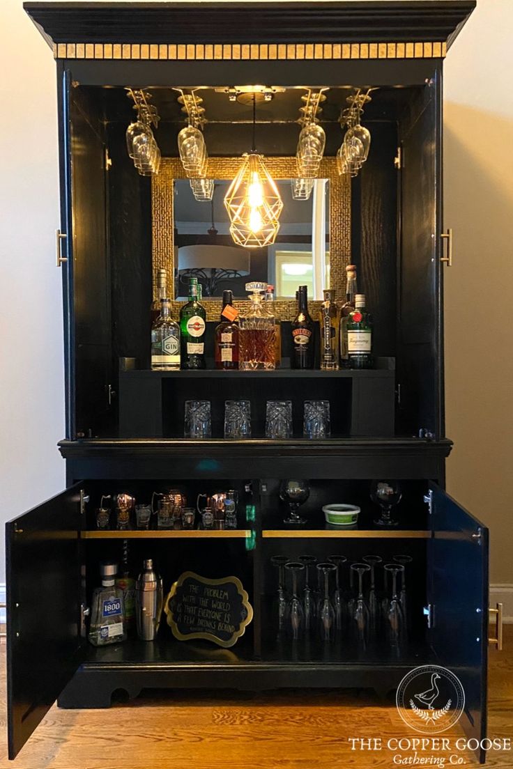 a bar with liquor bottles and glasses on it's side shelf, in front of a mirror