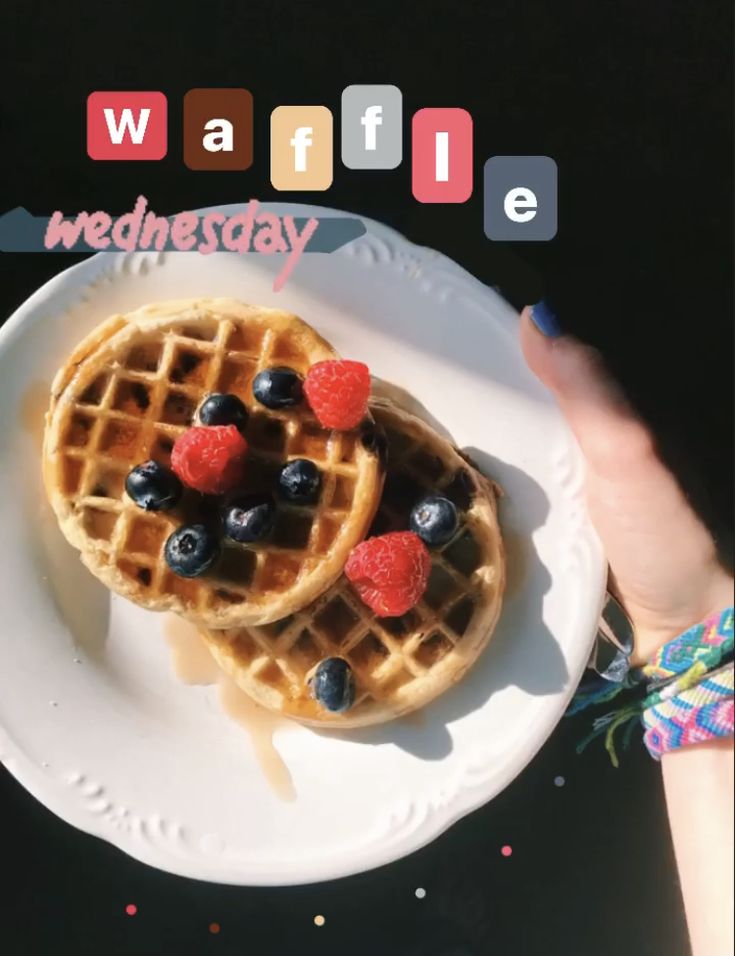 two waffles on a plate with blueberries and raspberries in the middle