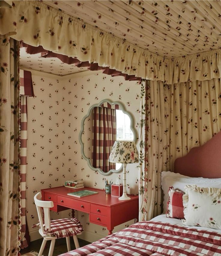 a red and white bed sitting under a window next to a dresser with a mirror on top of it