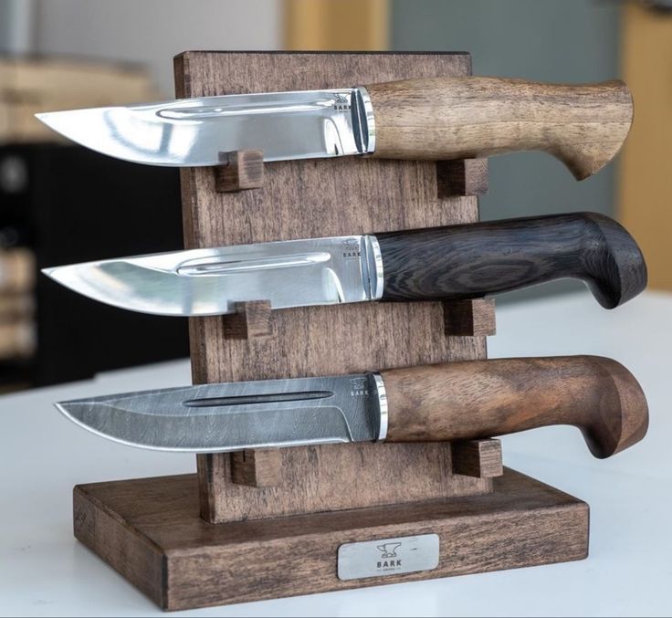 three knives are stacked on top of each other in a wooden holder with two knives sticking out of it