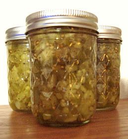 three jars filled with pickles sitting on top of a wooden table