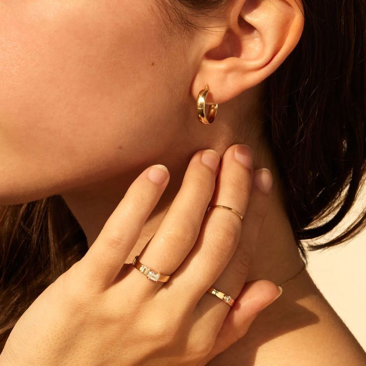 A woman holds her hand up to her neck that's visible because her long black hair is pulled away. This reveals the rings on her fingers and the hoop dangling from her ear. The tomboy hoop is a small flat ring of gold. Gold Punch, Catbird Jewelry, Gold Jewelry Gift, Diamond Signet Ring, Spring Gifts, Detailed Ring, Personalized Rings, 14k Gold Ring, Gifts For Wedding Party