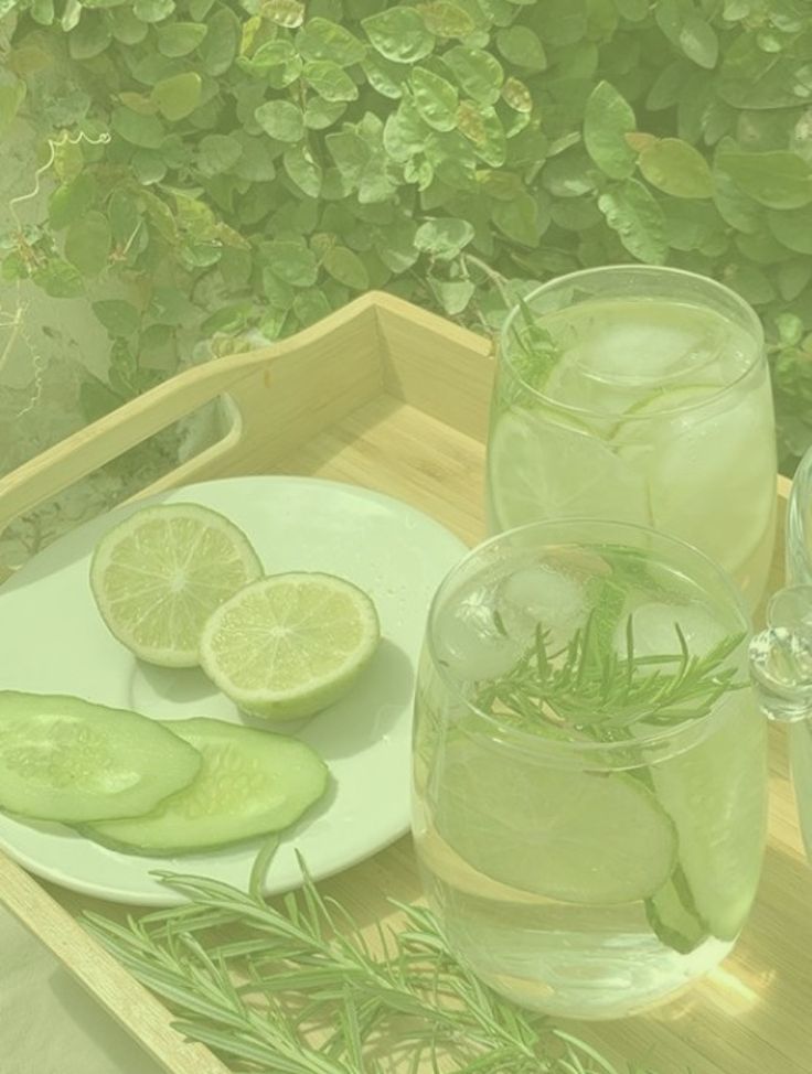 a tray with cucumbers, lemons and water on it