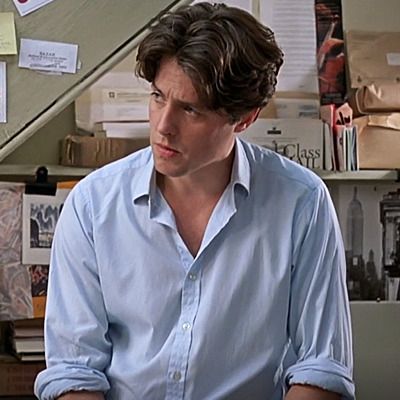 a man in a blue shirt sitting at a desk with papers on the wall behind him