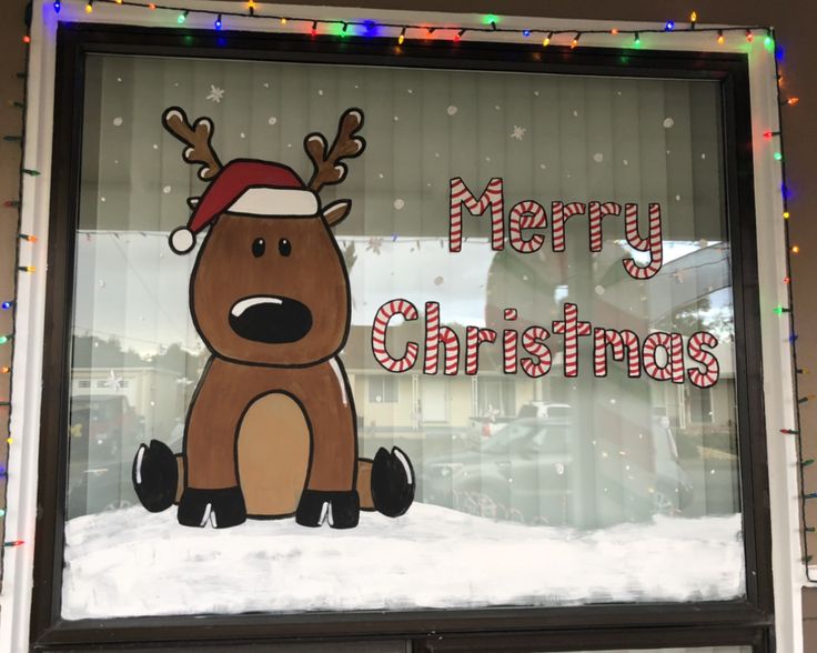 a merry christmas sign in the window of a store with reindeers on it's head