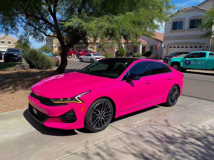 a pink car parked in front of a house