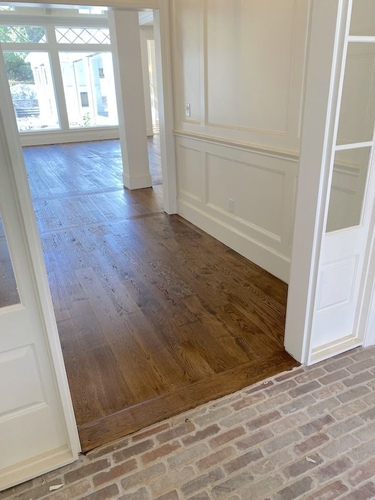 an empty room with hard wood floors and brick flooring on the side of the door