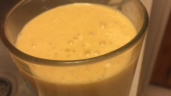 a glass filled with yellow liquid sitting on top of a counter next to a stove