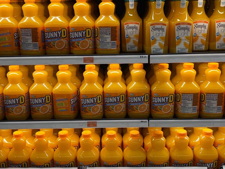 many orange juice bottles are on display in a store