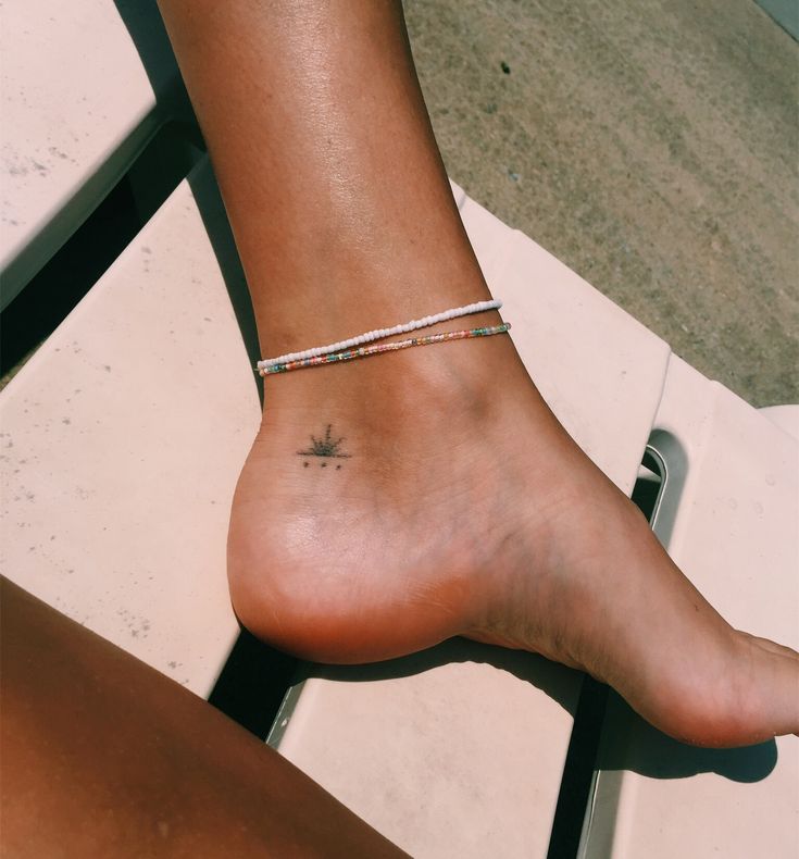 a woman's foot with a small star tattoo on her left ankle, sitting on a chair