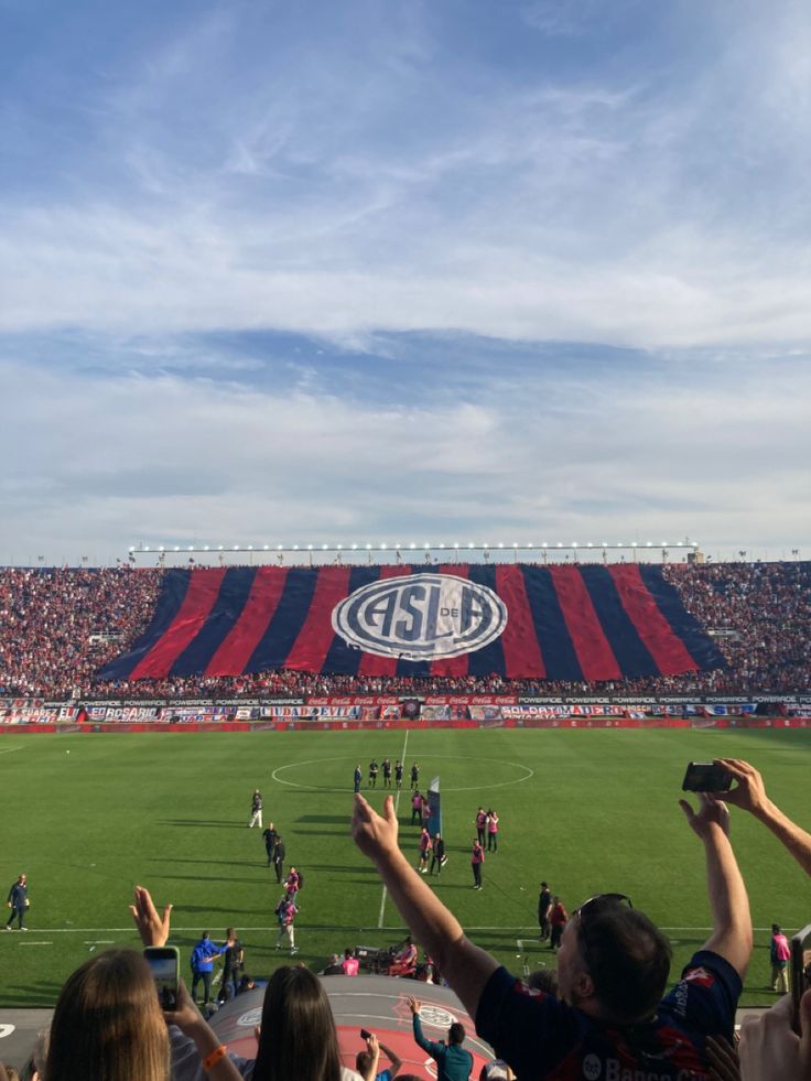 fans at a sporting event taking pictures with their cell phones in front of the stadium