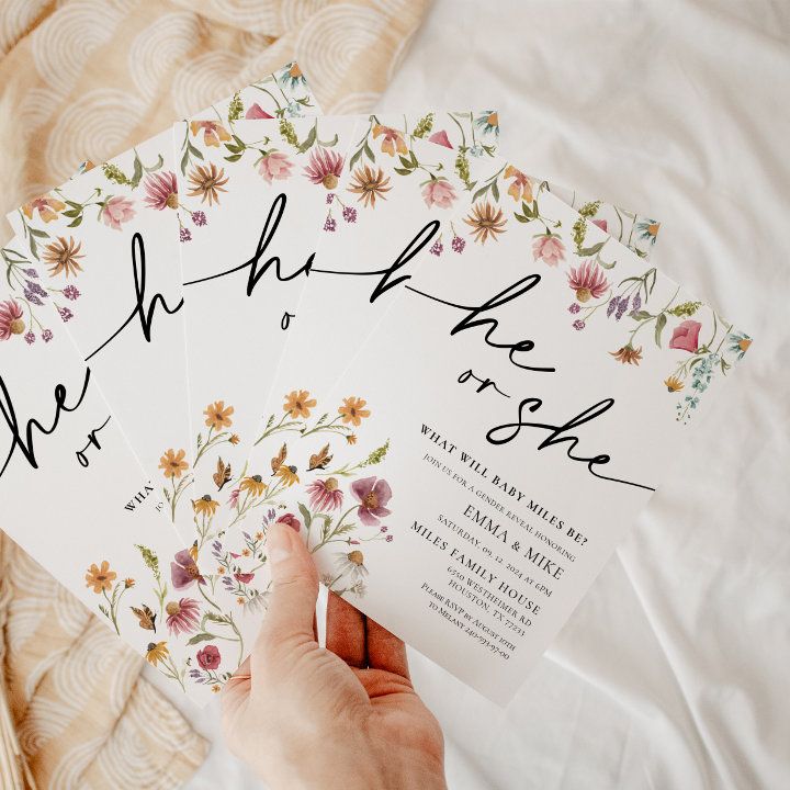 a person holding up some cards with flowers on them and writing the names in black ink