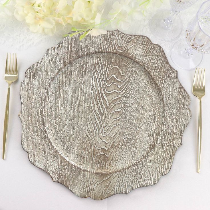 a silver plate sitting on top of a table next to two forks and knifes