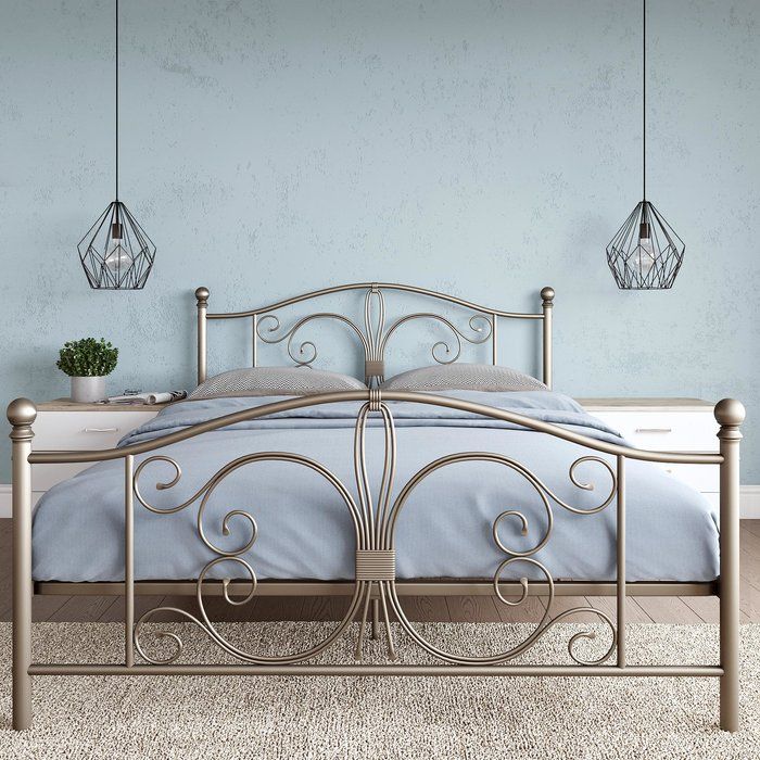 a metal bed frame with two lamps hanging from the ceiling above it in a bedroom